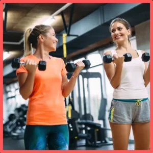 Two women lift weights together. 