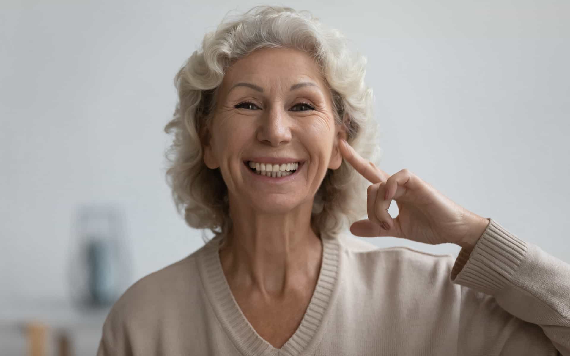 Woman Smiling pointing at ear