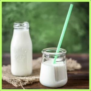 A pitcher and a glass of milk sit on a table. 