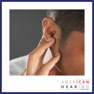 A man touches his ear. 