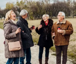 Two older couples laugh while they go for a walk.