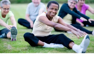 Five senior citizens do yoga outside.