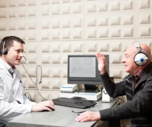An older man has a hearing test with an audiologist. 