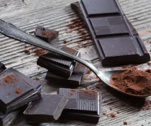 Pieces of dark chocolate are piled on a table. 