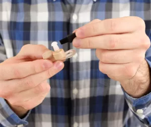 Close-up of hands working to fix a hearing aid. 