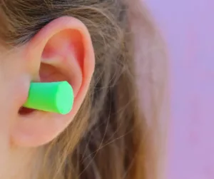 A green earplug inside a woman’s ear. 