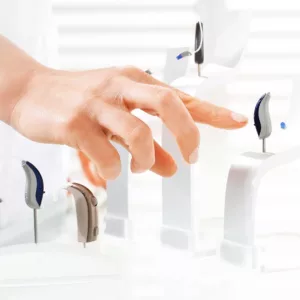 A finger points at a display of hearing aids.