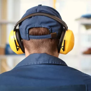 A man protects his hearing health by wearing ear muffs.