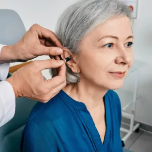 A hearing specialist fits a woman’s hearing aid. 
