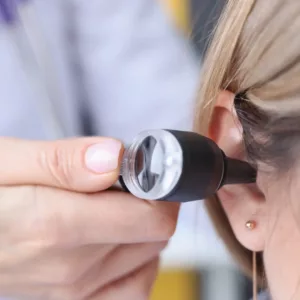 An otoscope is inserted into a woman’s ear. 