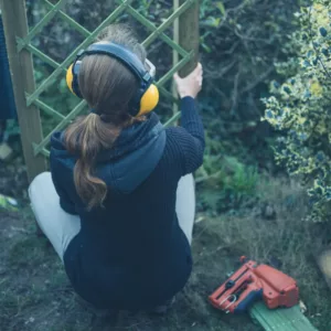A woman uses ear protection while building a fence.
