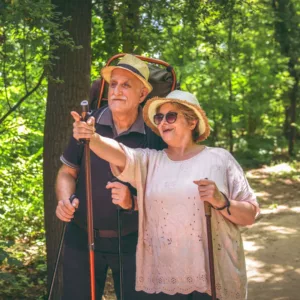 An older couple hikes in the woods. 