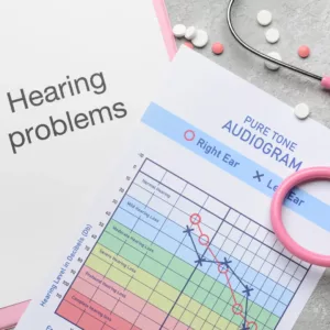 One paper shows the words “hearing problems,” and another shows an audiogram. 