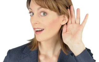 A woman cups her hand around her ear to hear better.