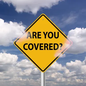 A yellow street sign asks, “Are you covered?” against a blue sky background.