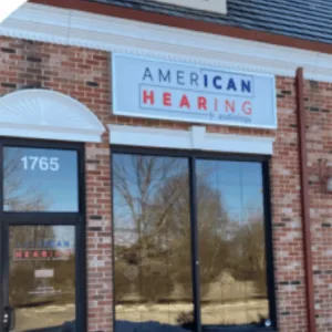 A brick storefront has an “American Hearing + Audiology” sign above it.