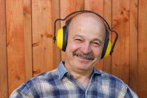 A man smiling while wearing ear protection. 