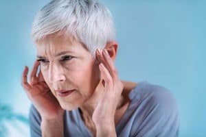 A woman holds her ears in discomfort.