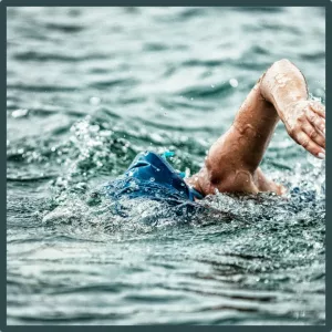 A person wearing a swim cap does the freestyle stroke.