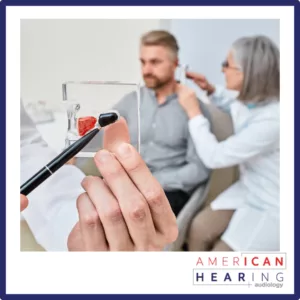 An audiologist puts a hearing aid in a man's ear. 