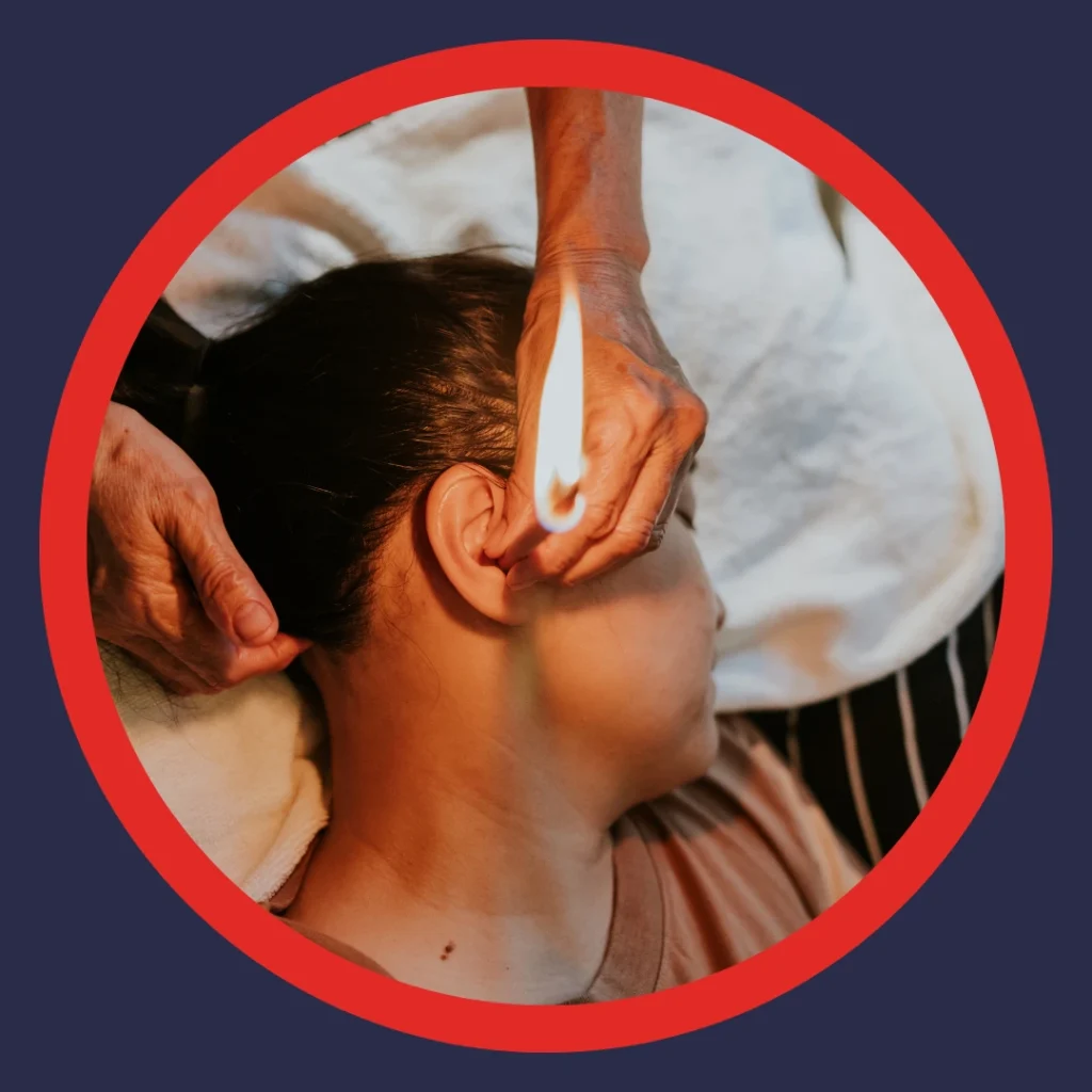 Someone holds a lit candle next to a woman's ear.