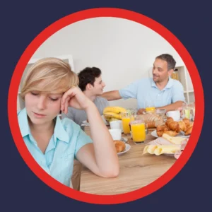 A woman looks sad as a conversation goes on around her.