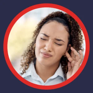 A woman holds her ear and grimaces.