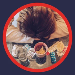 A person rests her head next to medicine and tissues.