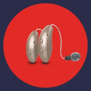 A pair of hearing aids sit on a red background. 