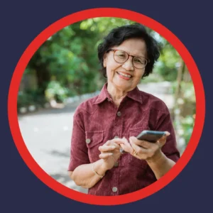 An older woman smiles while holding her phone. 