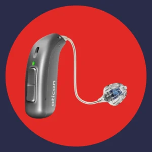 A silver Oticon Real hearing aid sits on a red background. 