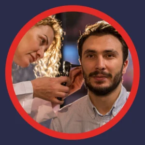 An audiologist looks in a man's ear.